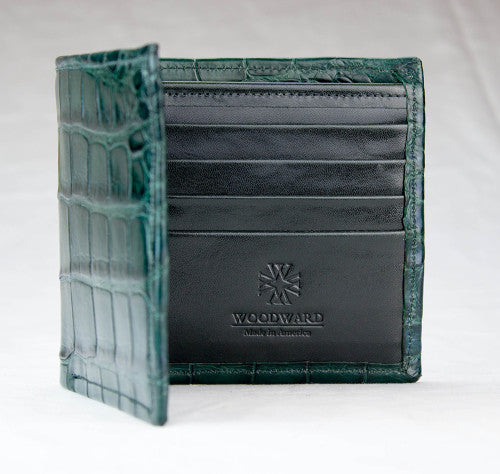 A matte green alligator wallet with the interior visible, showing multiple card slots and the brand name 'Woodward' embossed on the leather.